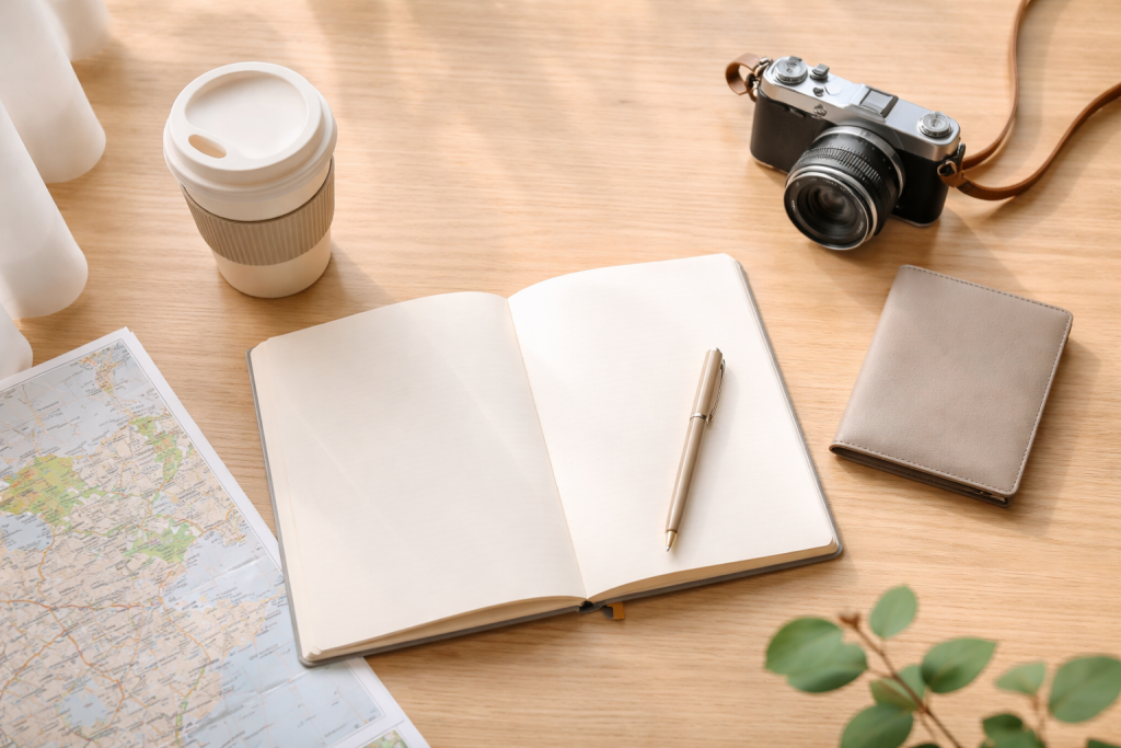[light] Standard blogheader: et roligt flat lay af rejseplanlægning med notesbog, pen, pas-cover, kamera og en kop kaffe i blødt vindueslys. Neutral og genbrugelig på mange emner.